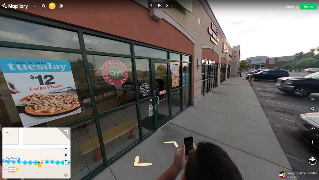 Mapillary website showing a 360 degree panoramic image of a strip mall area in its web interface. OSM Utah mapper dknelson is visible in the shot using his regular phone to capture additional detail.